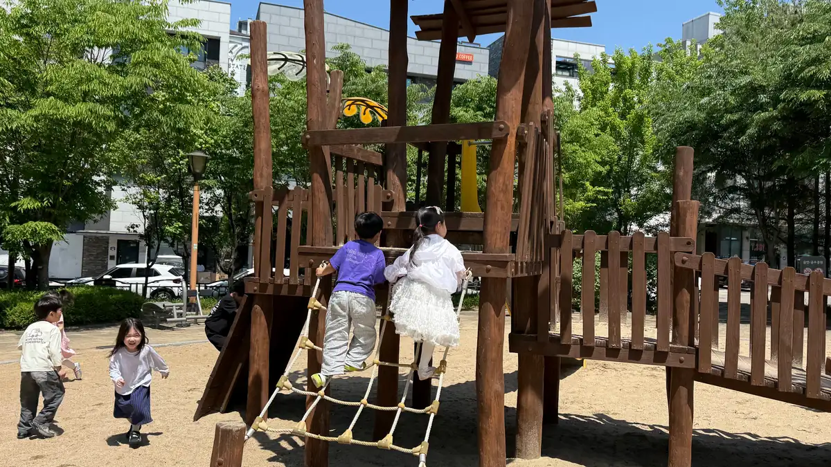 나무로 만든 놀이 구조물에 오르는 아이들
